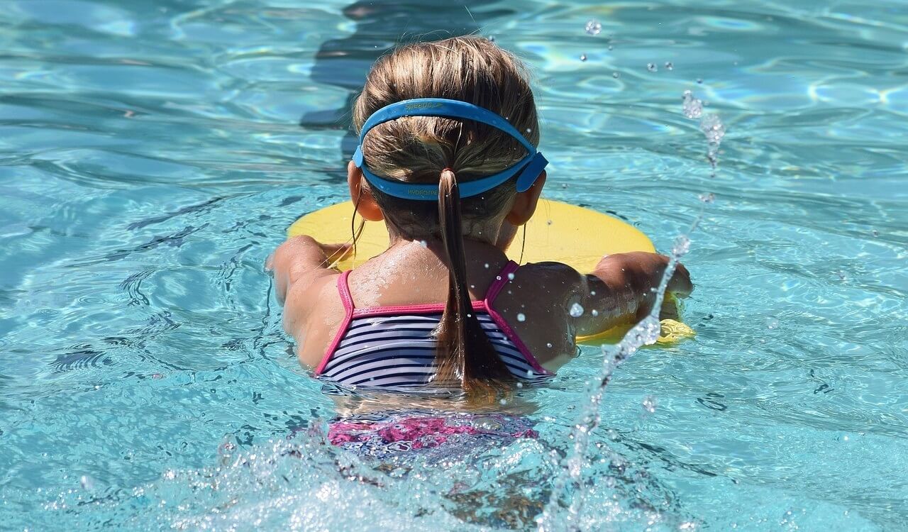 Back of a young girl swimming in a clean outdoor pool