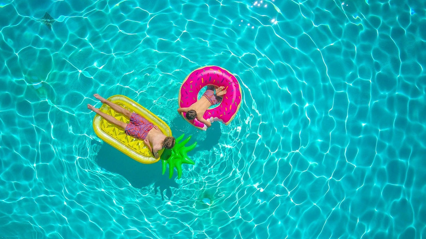 Brothers floating on rafts in an in-ground pool
