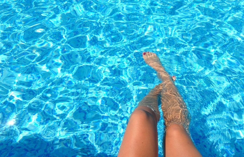 Woman dipping feet into a clean pool