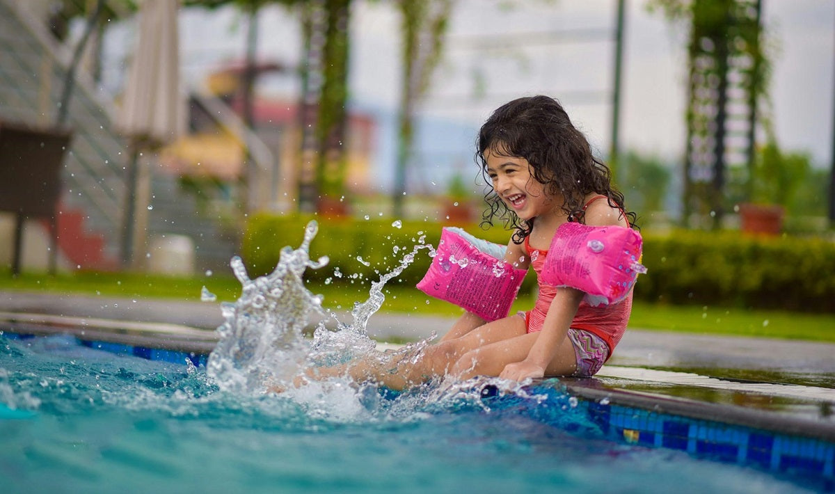 Little girl splashing her legs in an in-ground pool