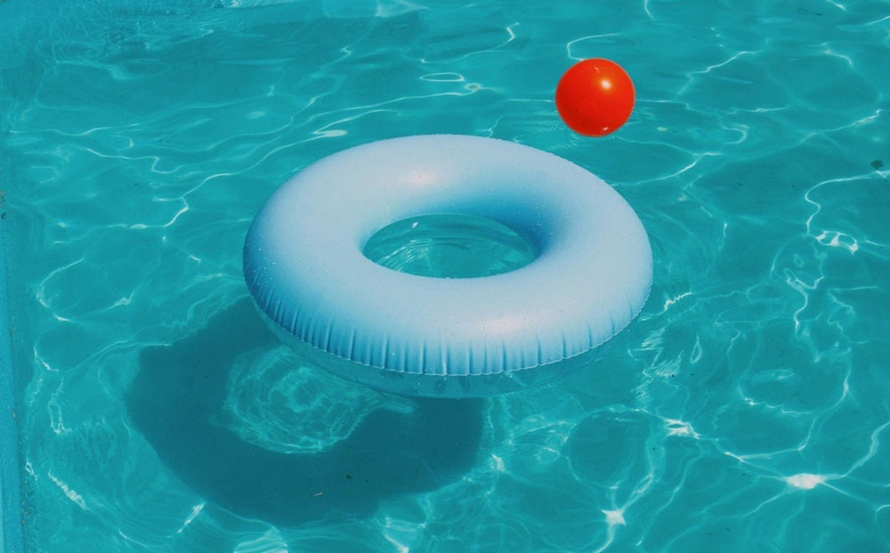 Pool ring and red ball floating in a swimming pool