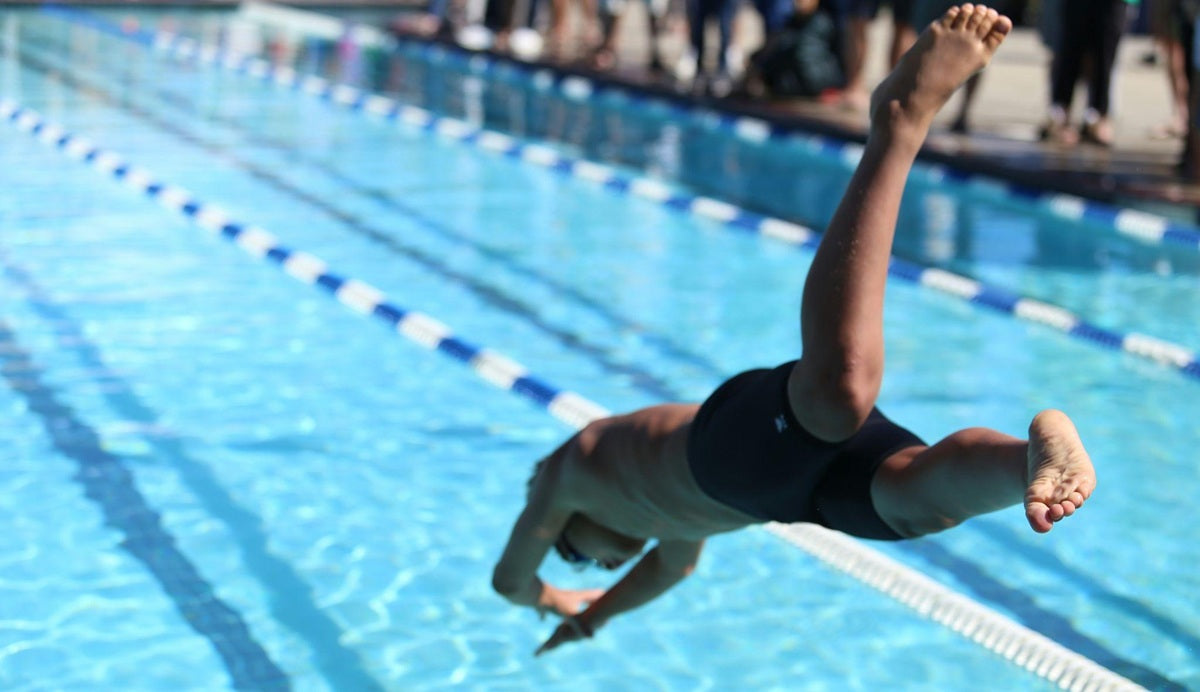 Teenage swimmer diving into a public pool