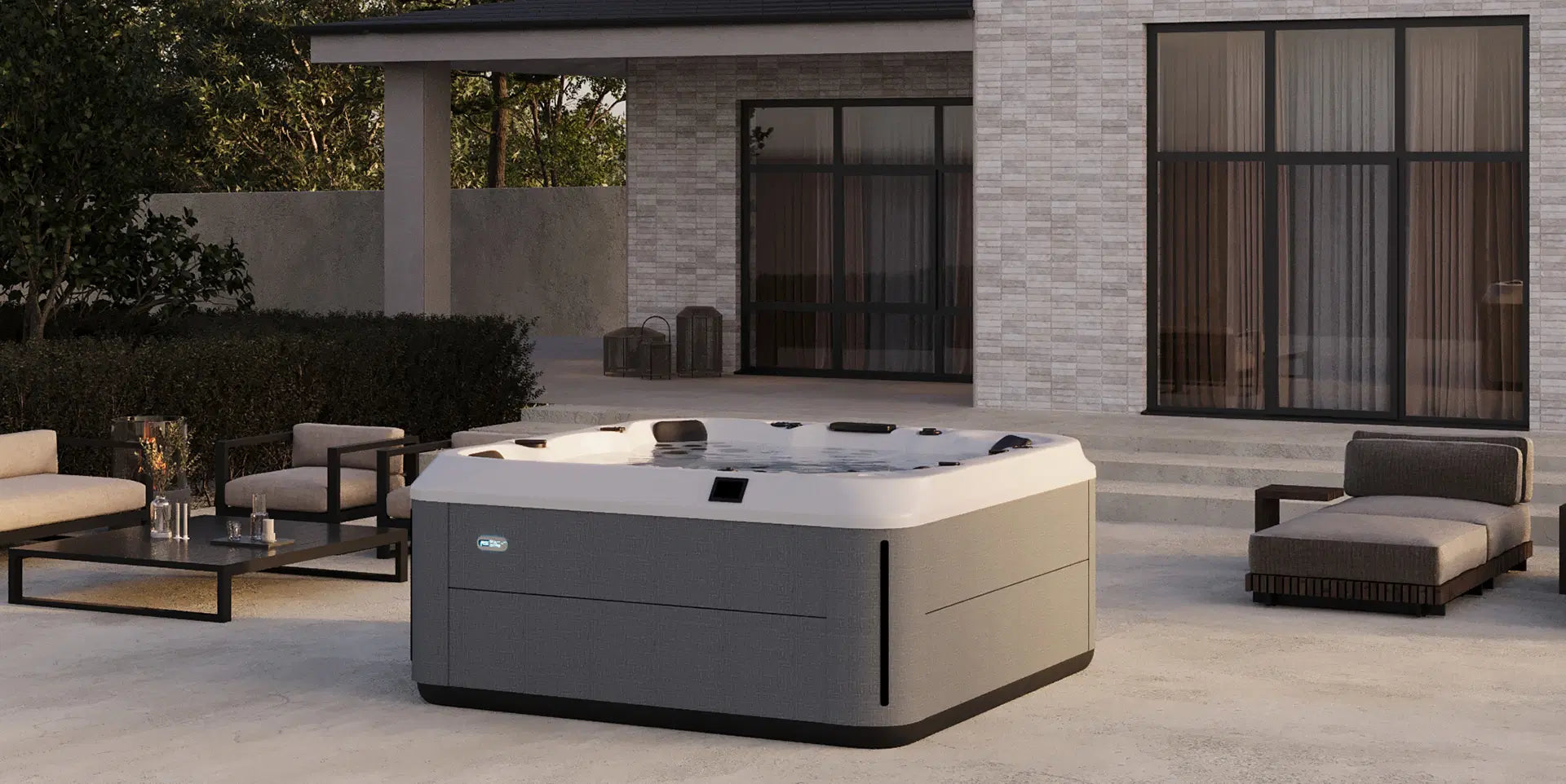 Hot tub in a modern outdoor patio setting with furniture and a building in the background sold from Pool Products Canada in Collingwood Ontario. Hot tubs and swim spas in Collingwood and Thornbury.